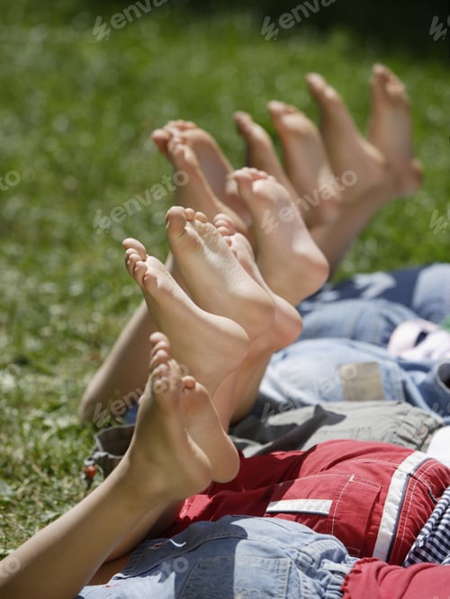Preview: Close Up Of Children Laying In Grass With Bare Feet In Air