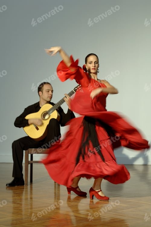 Preview: Blurred View Of A Young Woman Flamenco Dancing As A Young Man Plays A Guitar Beside Her