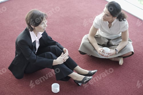 Preview: Two Businesswomen Sitting On Floor Talking