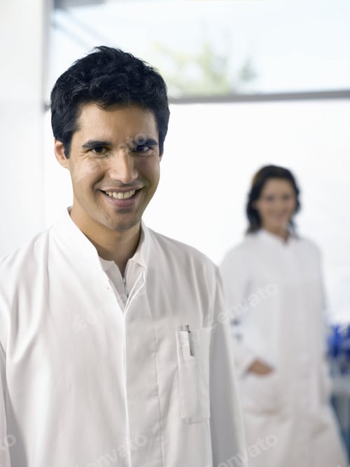 Preview: Male Scientist Smiling With Co-Worker In Background