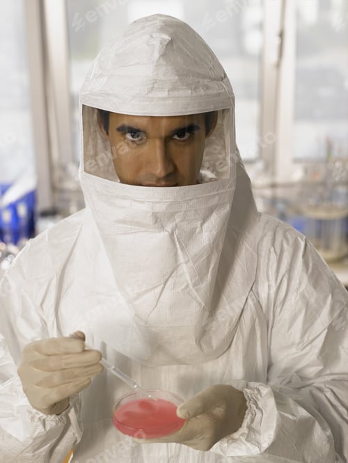 Preview: Male Scientist In Protective Suit Examining Substance In Petri Dish