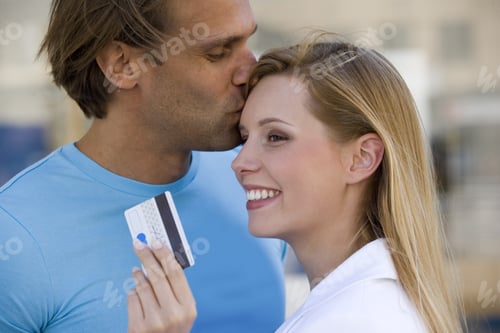 Preview: Woman Holding Credit Card While Boyfriend Kisses Her Forehead