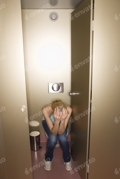 Preview: Woman Sitting In Public Restroom With Head In Hands