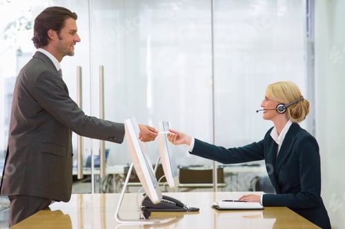 Preview: Mature Businessman Shaking Hands With Woman Wearing Headset At Desk