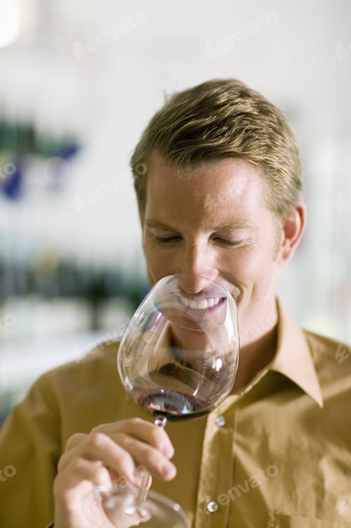 Preview: Man Smelling Red Wine In Glass At Wine Tasting