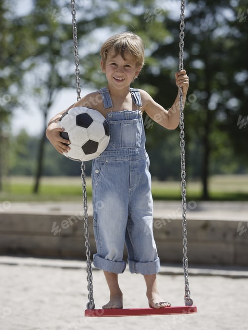Preview: Boy Standing On Swing Holding Soccer Ball