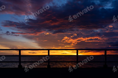 Preview: Silhouette Fence With Sunset Sky And Color Clouds Into The Twilight At The Lake.