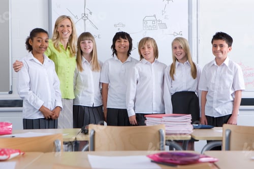 Visualização: Uma visão ampla de uma professora feliz orgulhosamente em pé com seus alunos em uma sala de aula com um