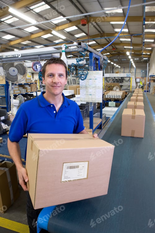 Preview: Worker Holding The Final Packaged Box Picked Up From The Assembly Line In A Large Factory