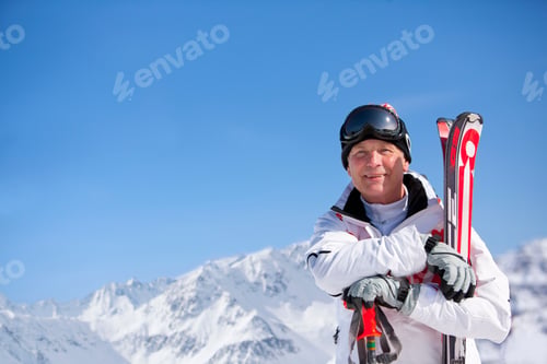 Preview: A Medium Shot Of A Smiling Man Standing While Holding Skis In Snow.