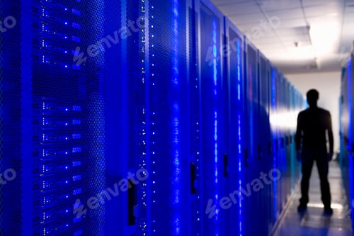 Preview: Bright Blue Glowing Row Of Network Server Cabinets In Selective Focus With A Blurry Silhouette Of