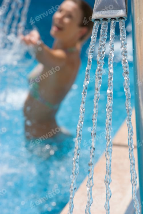 Preview: A Close Up Portrait Shot Of A Swimming Pool Shower With An Enthusiastic Woman In The Background.
