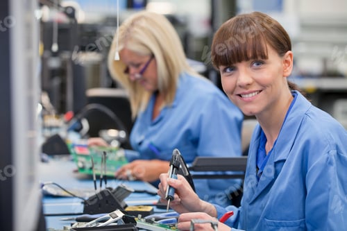 Preview: Horizontal Profile Shot Of A Female Technician In An Assembly Line Looking Up While Soldering A