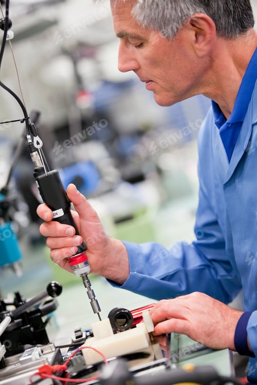 Preview: Vertical Tilted Profile Shot Of A Technician Screwing On A Component Using An Overhead Mechanized
