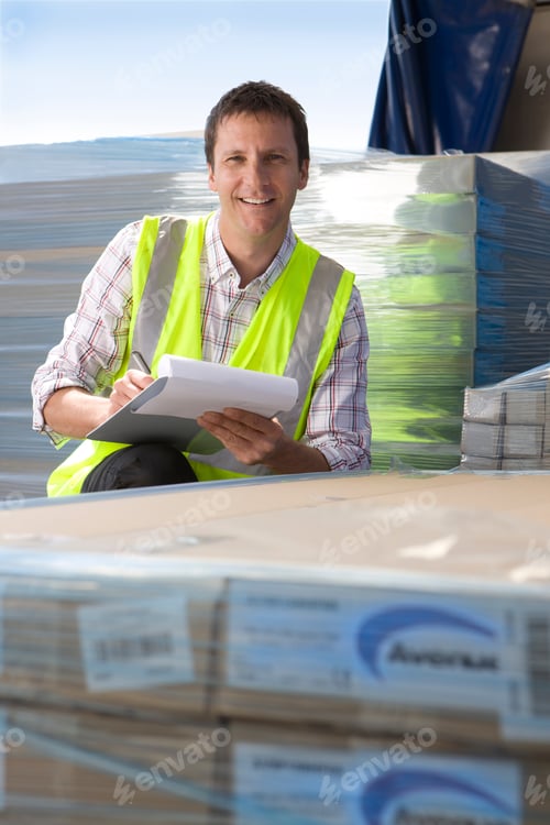 Preview: A Worker In Selective Focus Sitting Around Large Boxes Of Merchandise A Pen And A Clipboard