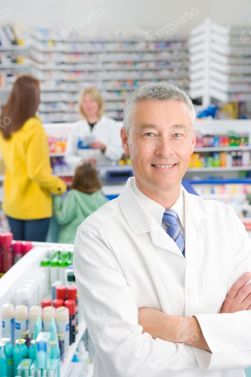 Preview: A Portrait Shot Of A Pharmacist Standing With His Hands Crossed And Looking At Camera In A Pharmacy