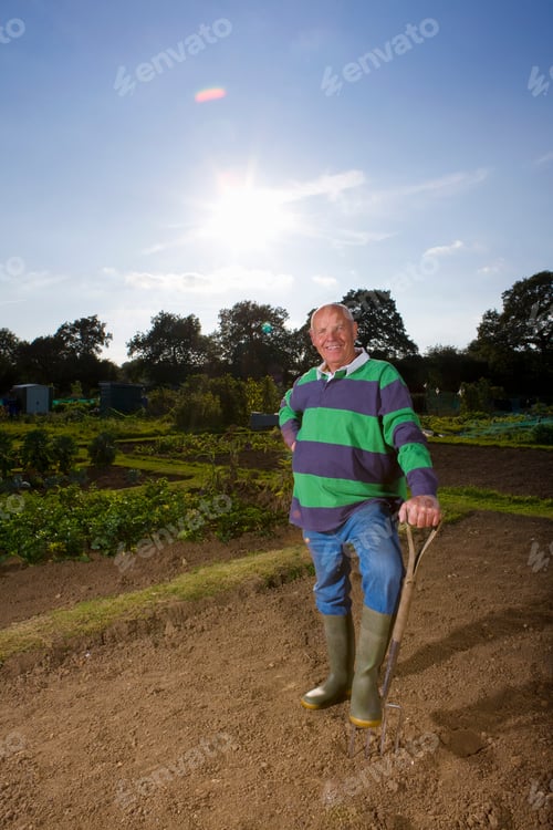 Preview: A Portrait Shot Of A Smiling Old Man Holding A Spade Fork In A Garden.