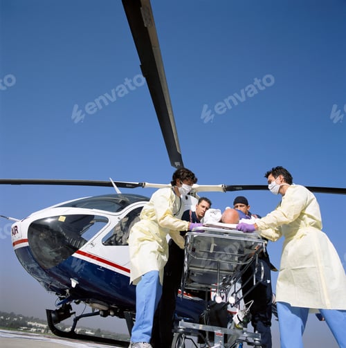 Preview: A Tilted Low Angle View Of A Serious Patient Being Rushed By Doctors And Paramedics On Gurney From