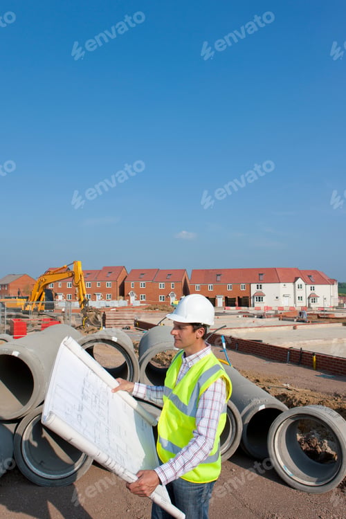 Preview: A High Angle Side Profile Portrait Shot Of An Architect Reviewing Blueprints At A Construction Site