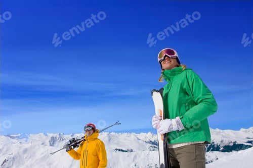 Preview: Medium Wide Of A Smiling Couple Standing On A Snowy Mountain Holding Skis On A Bright Sunny Day