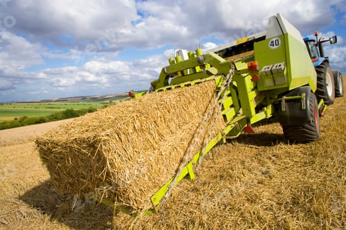 Preview: A Backside View Of Blue Tractor And A Baler Baling Straw In Rural Field.