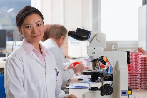 Preview: A Medium Shot Of A Female Technician Smiling At Camera While Working With A Microscope In A