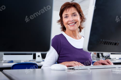 Preview: A Medium Shot Of A Senior Woman Sitting Behind A Monitor And Smiling At The Camera A Computer In A