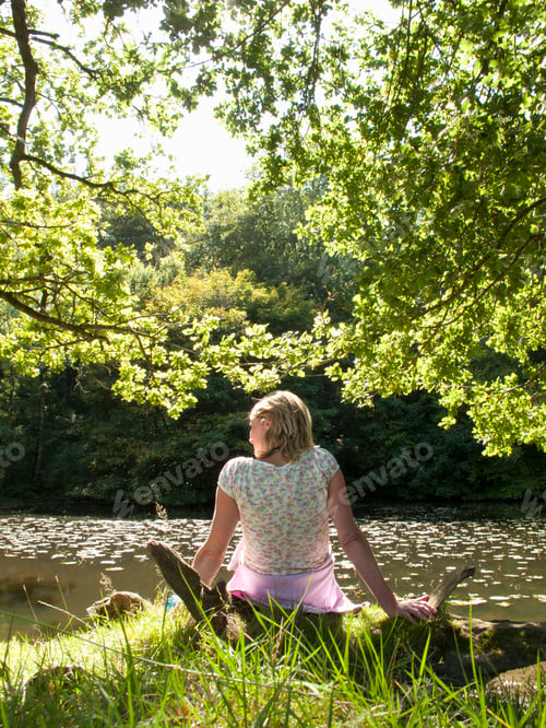 Preview: A Portrait Shot Of A Blonde Woman From Backside Relaxing On A Riverbank.