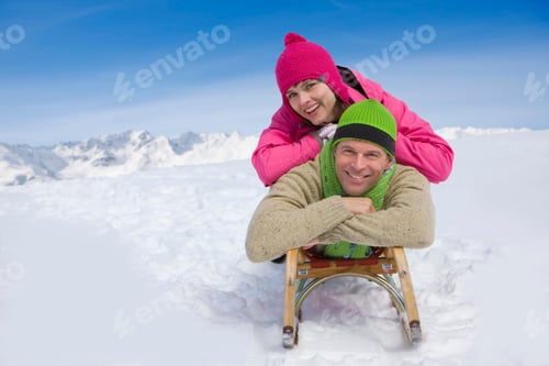 Preview: A Portrait Of A Good Looking Couple Lying On A Sled With Their Arms Crossed While Smiling At The
