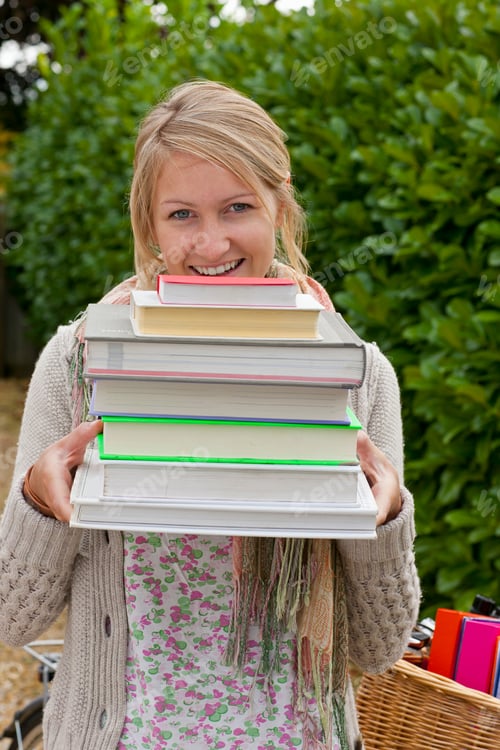 Preview: A Portrait Shot Of A Happy Young Blonde Woman Holding A Stack Of Textbooks.
