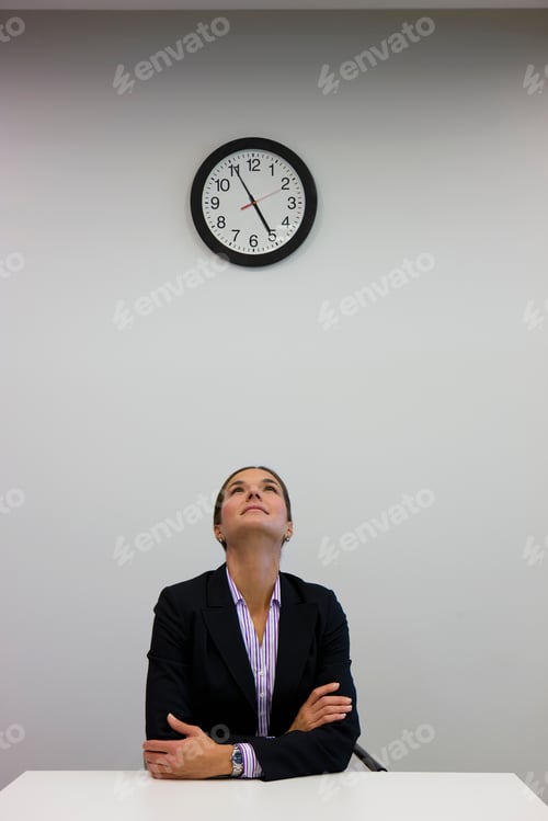 Preview: A Vertical Shot Of A Businesswoman Looking Up At A Clock In Office.