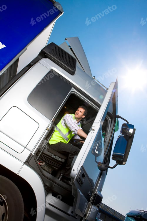Preview: A Slanted Low Angle Vertical Shot Of A Truck Driver In Safety Vest Sitting Inside The Cab Of A