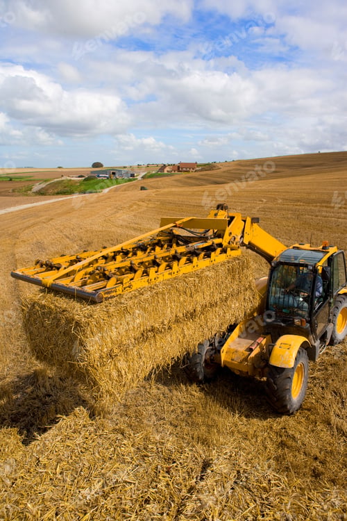 Preview: A High Angle Portrait Shot A Yellow Tractor Stacking Straw Bales In A Sunny Rural Field.
