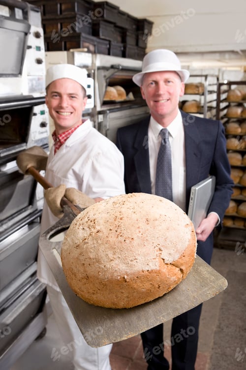 Preview: A Portrait Shot Of A Smiling Baker Showing Fresh Bread To The Camera As He Removes It From Oven