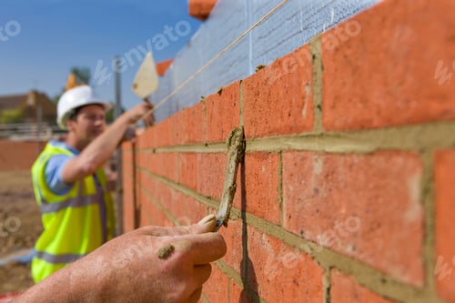 Preview: Bricklayers Using Trowels To Apply And Level The Mortar Between Bricks In Selective Focus