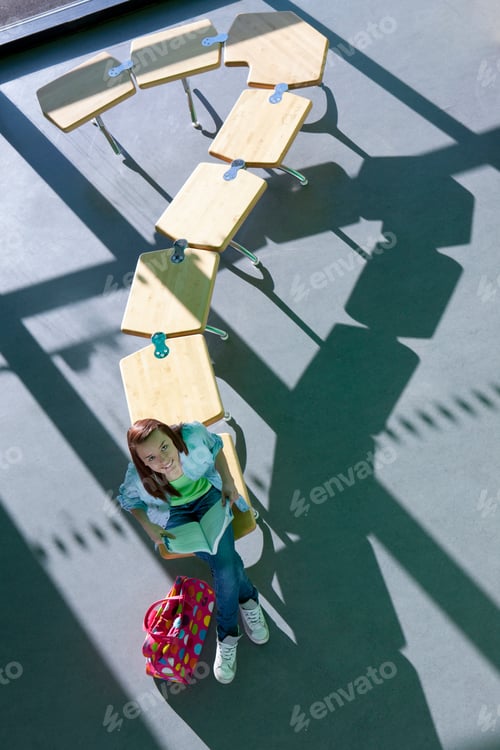 Preview: A High Angle Vertical Shot Of A Young Smiling Girl Looking Up While Sitting At The End Of A Row Of