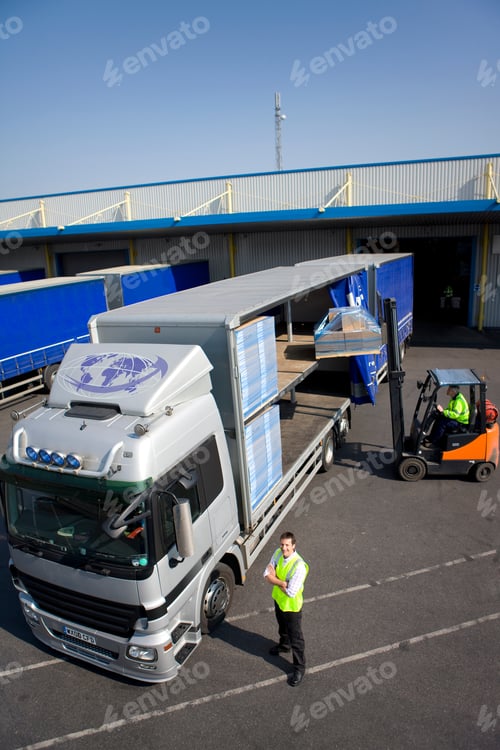 Preview: A Vertical Top Angle Shot Of A Loading Dock With A Worker Smiling At The Camera With Crossed Arms
