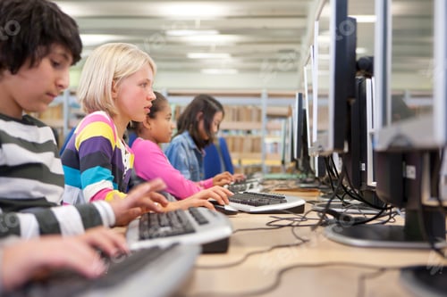 Preview: A Medium Shot Of A Young Blonde Girl Using Computer In A School Computer Lab With Other Students.