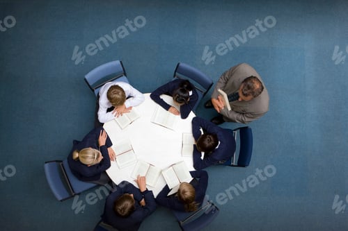 Preview: A Top Angle Medium Shot Of A Teacher Watching His Students Reading Books At A Round Table.