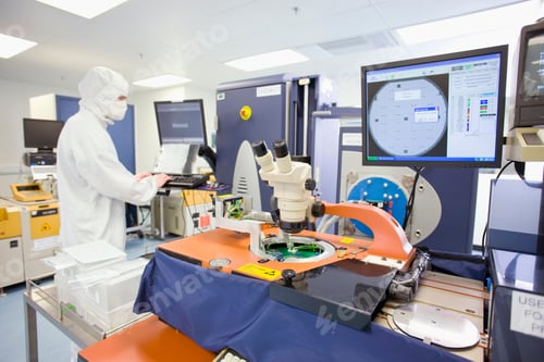 Preview: An Engineer In Clean Suit Working On A Computer In A Fully Equipped Silicon Wafer Manufacturing