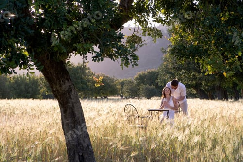 Preview: A Wide Shot Of A Man Saying Something In His Girlfriend'S Ear At A Table In Rural Field.