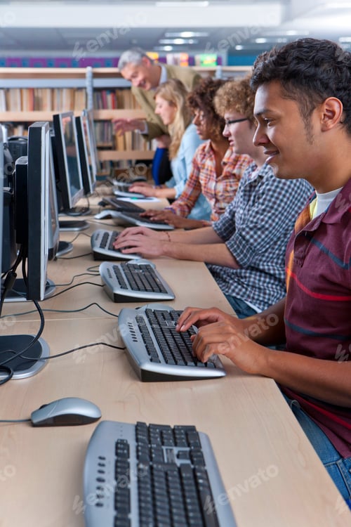 Preview: A Portrait Shot Of A Happy Young Man Using A Computer In A Computer Lab With Other Students In