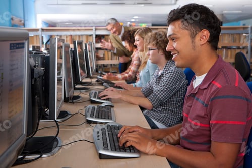 Preview: A Medium Shot Of A Happy Young Man Using A Computer In A Computer Lab With Other Students In