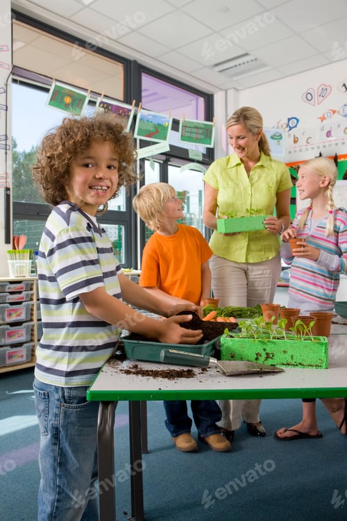 Preview: A Portrait Shot Of A Young Boy Smiling At The Camera While Filling Soil In The Pot With Teacher And