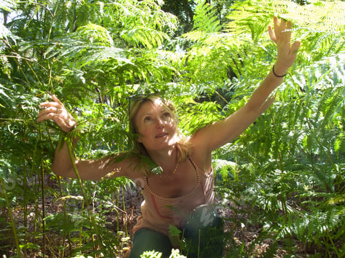 Preview: A Woman Sitting Among Plants And Looking Up In A Forest.
