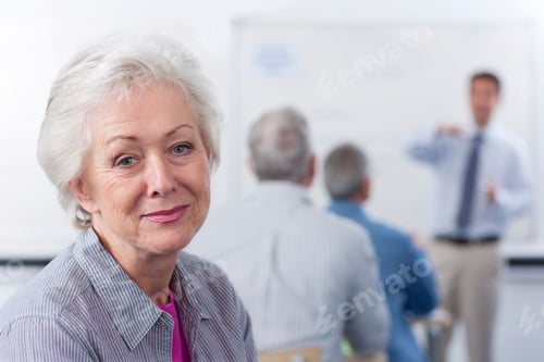 Preview: A Close Up Shot Of A Senior Woman With Gray Hair Looking At Camera With Teacher Teaching In