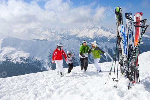 Preview: A Happy Family Of Four Geared Up While Having Fun In The Snow With Bunch Of Skis Standing In The