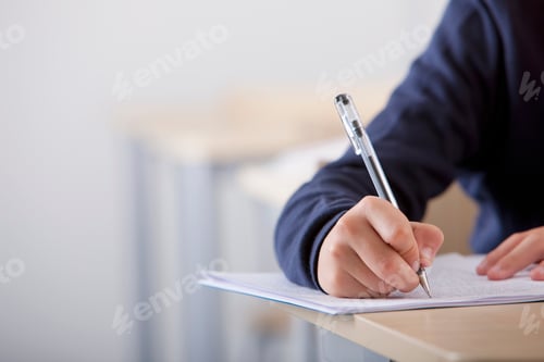 Preview: A Close Up Shot Of A Student'S Hand Writing Exam At His Desk.