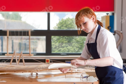 Preview: A Medium Shot Of A Young Girl Working On A Wooden Airplane Model In A Class.