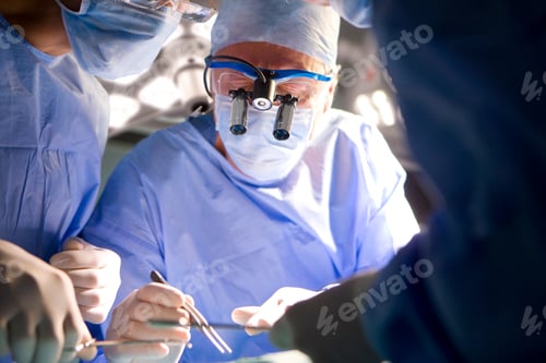 Preview: A Senior Surgeon Wearing Surgical Binocular While Performing An Intricate Operation With His